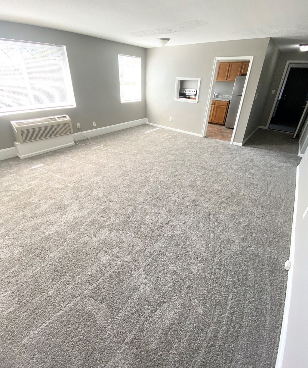 an empty living room with a carpeted floor