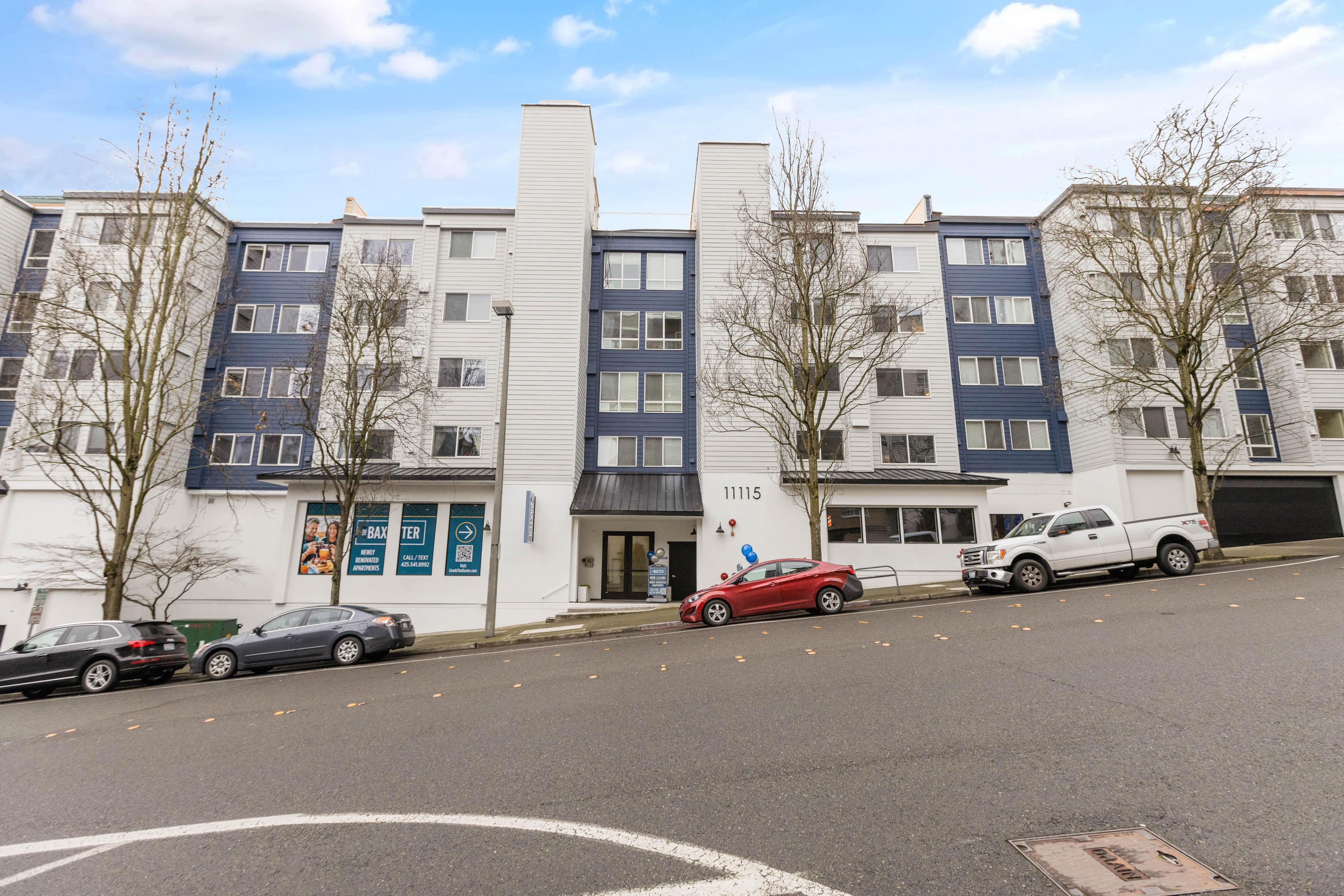 a city street with cars parked in front of an apartment building