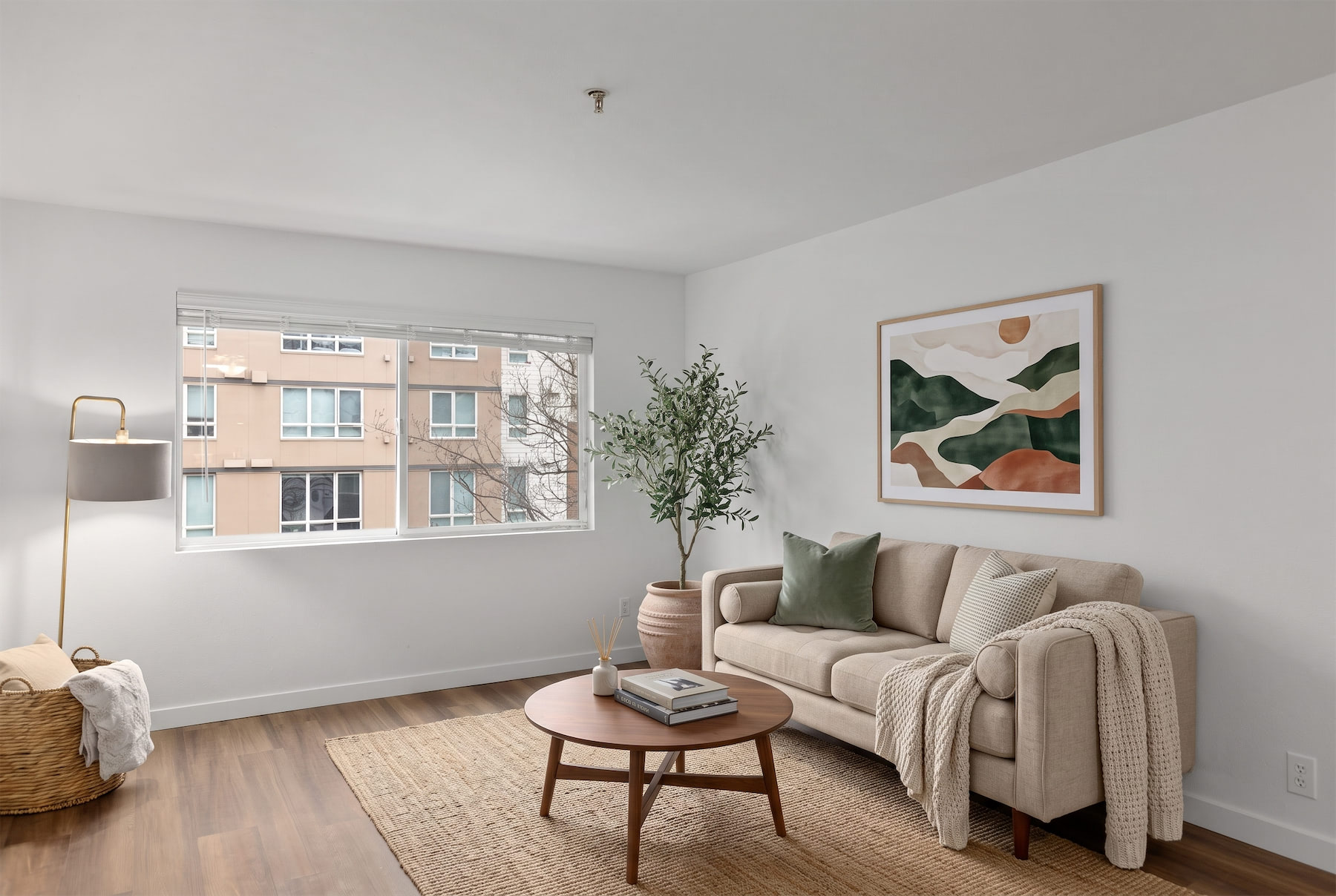 A living room with a couch, a table, a plant, and a painting on the wall.