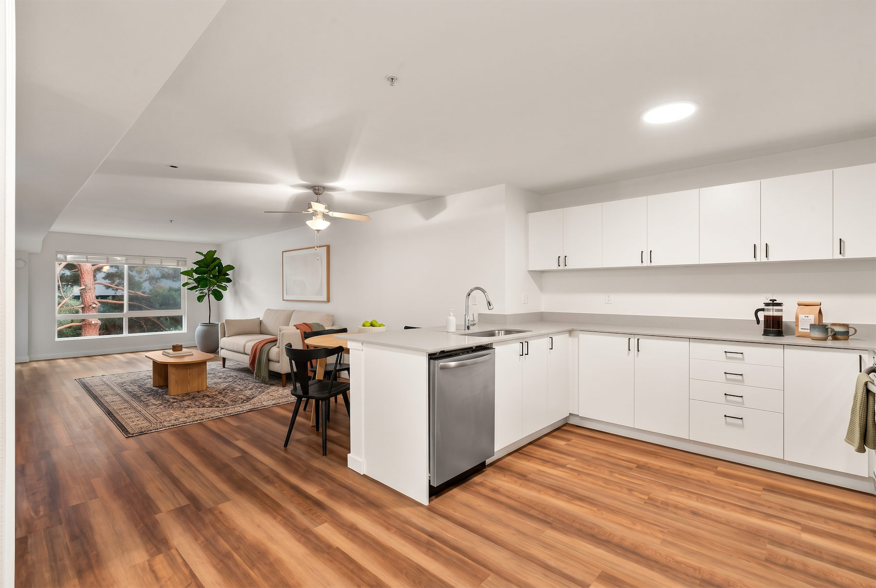 A modern kitchen with white cabinets and a wooden floor.