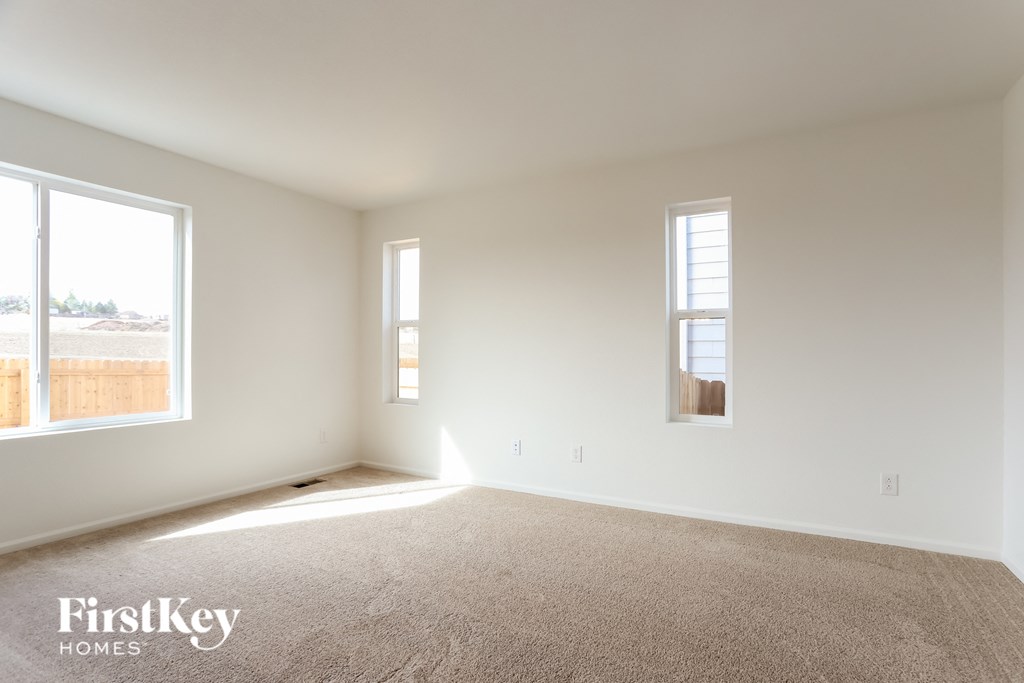 an empty room with two windows and a carpet