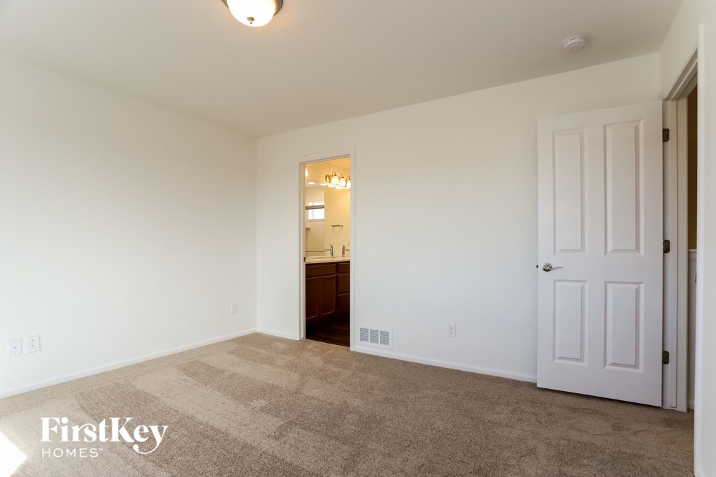 an empty living room with a white door to a bathroom