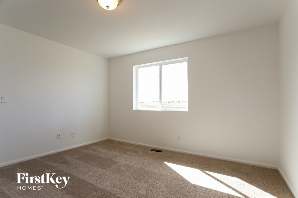 a bedroom with white walls and a window
