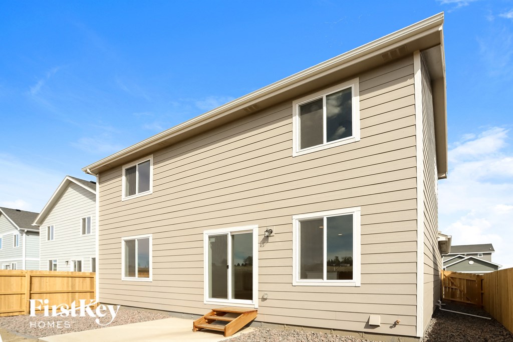 the exterior of a house with tan siding and a wooden fence