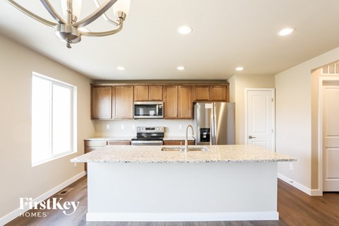 A kitchen with a granite countertop and wooden cabinets.