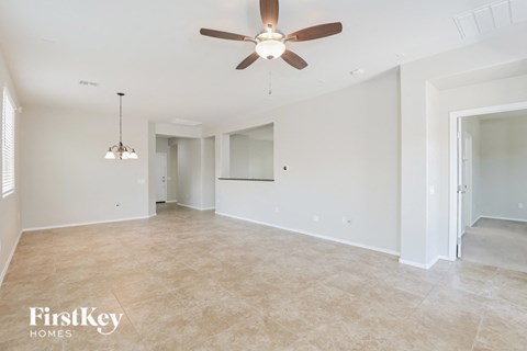 A spacious room with a ceiling fan and a hanging light fixture.