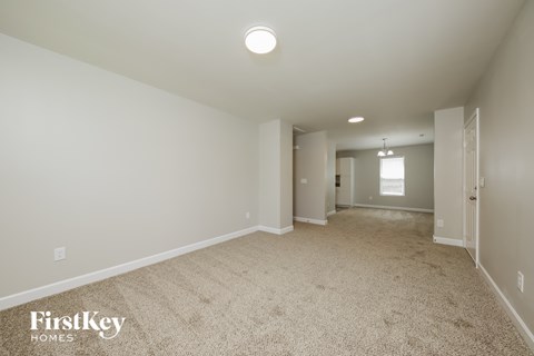 a spacious living room with carpet and white walls