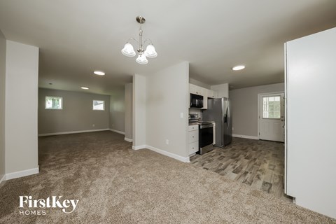 a spacious living room with a kitchen with a stove and refrigerator