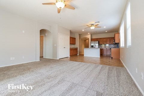 A spacious living room with a carpeted floor and a ceiling fan.