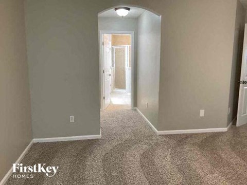a hallway with a carpeted floor and a door to a bedroom