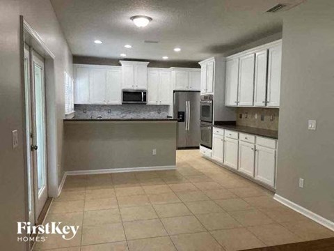 a large kitchen with white cabinets and stainless steel appliances