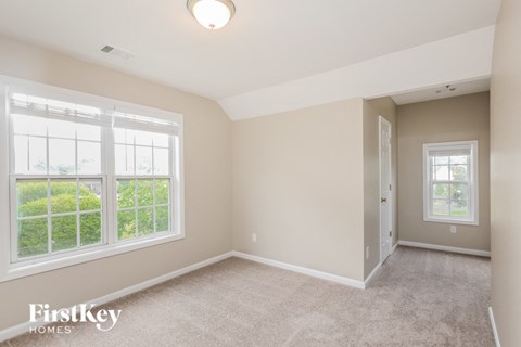 a bedroom with two large windows and a carpeted floor