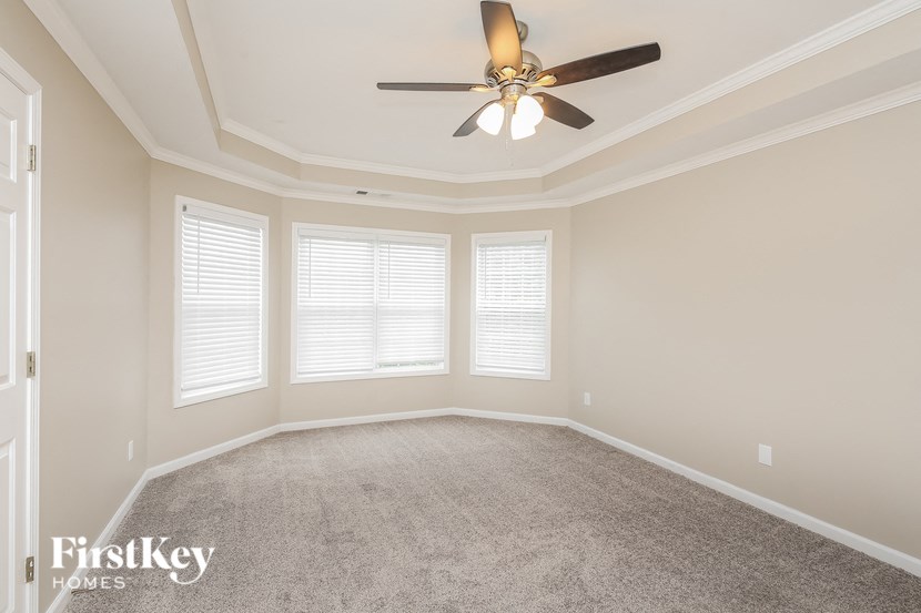 an empty room with a ceiling fan and three windows