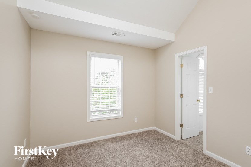 a bedroom with a door and a window and a carpeted floor