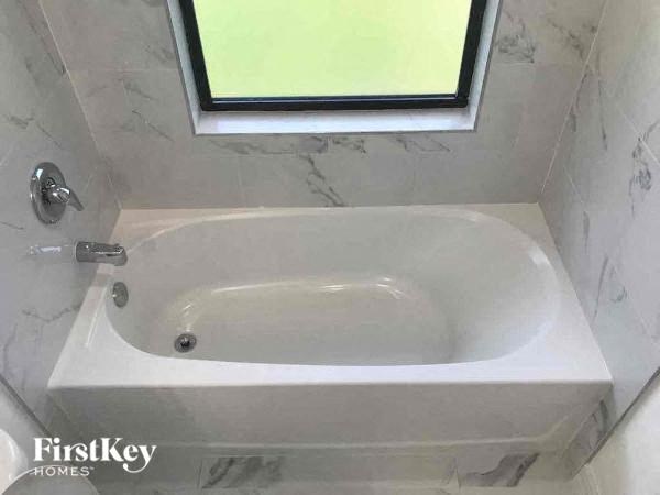 a white bath tub sitting under a window in a bathroom