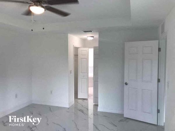 an empty living room with white walls and a ceiling fan