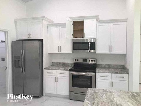 a kitchen with white cabinets and stainless steel appliances