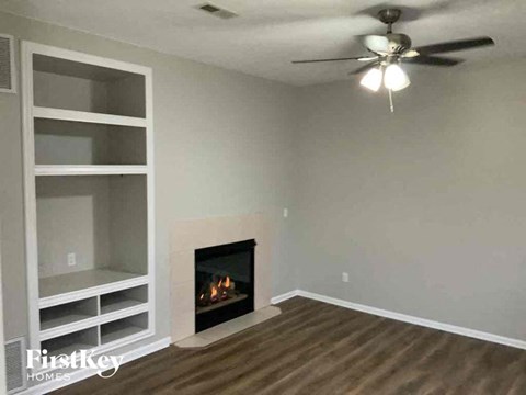A living room with a fireplace and a ceiling fan.