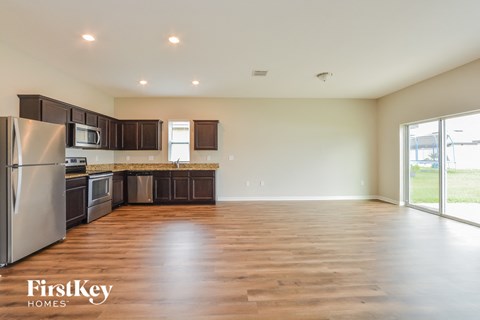 A spacious kitchen with wooden floors and a refrigerator.