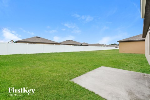 A grassy area with a concrete slab in the foreground and houses in the background.