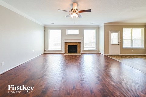 A spacious room with wooden floors and a fireplace.