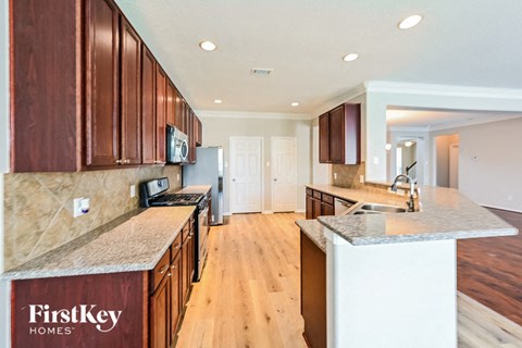 A kitchen with wooden cabinets and a countertop that says FirstKey Homes.