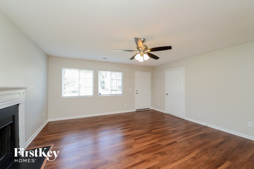 A spacious room with a fireplace and wood flooring.