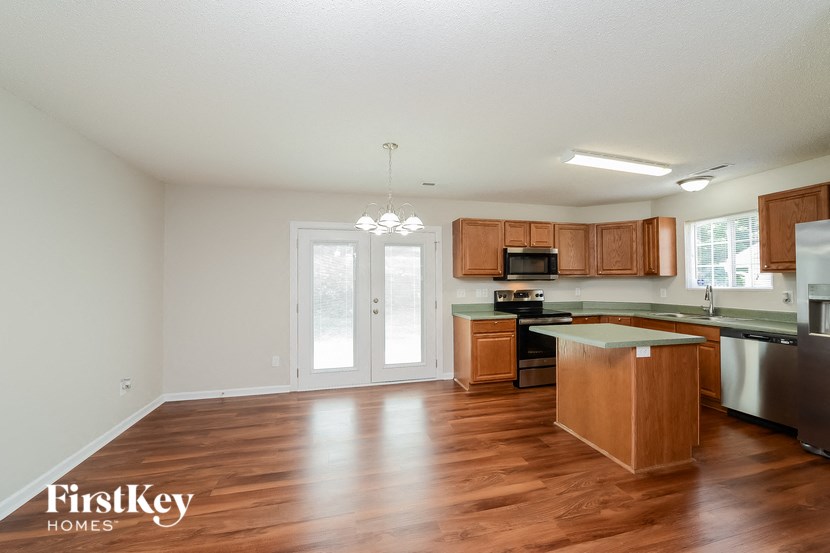 A kitchen with wooden floors and a stainless steel refrigerator.