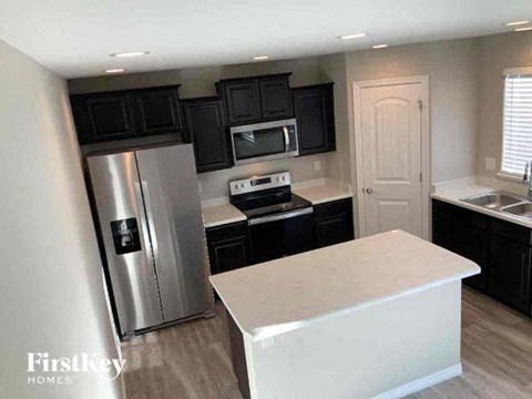 a kitchen with black cabinets and a stainless steel refrigerator