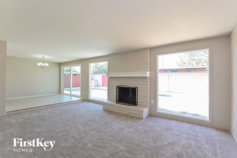 A spacious living room with a fireplace and large windows.