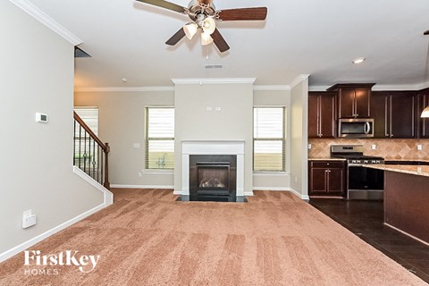 a kitchen with a living room with a fireplace and a ceiling fan