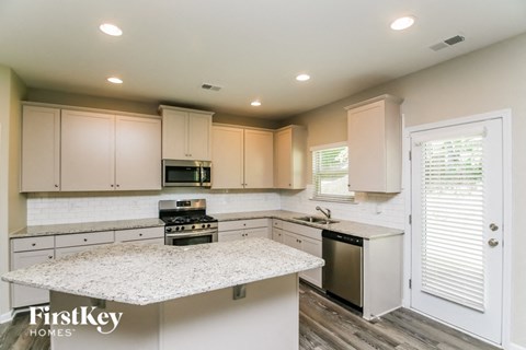 a kitchen with white cabinets and a marble counter top