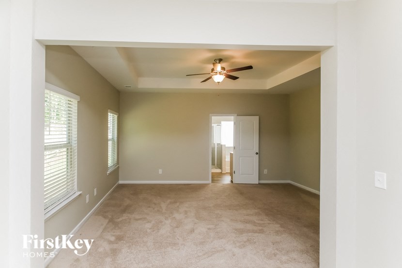 an empty living room with a ceiling fan and window