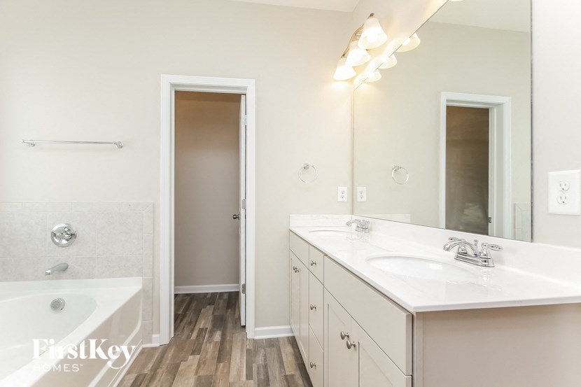 a bathroom with two sinks and a tub and a mirror