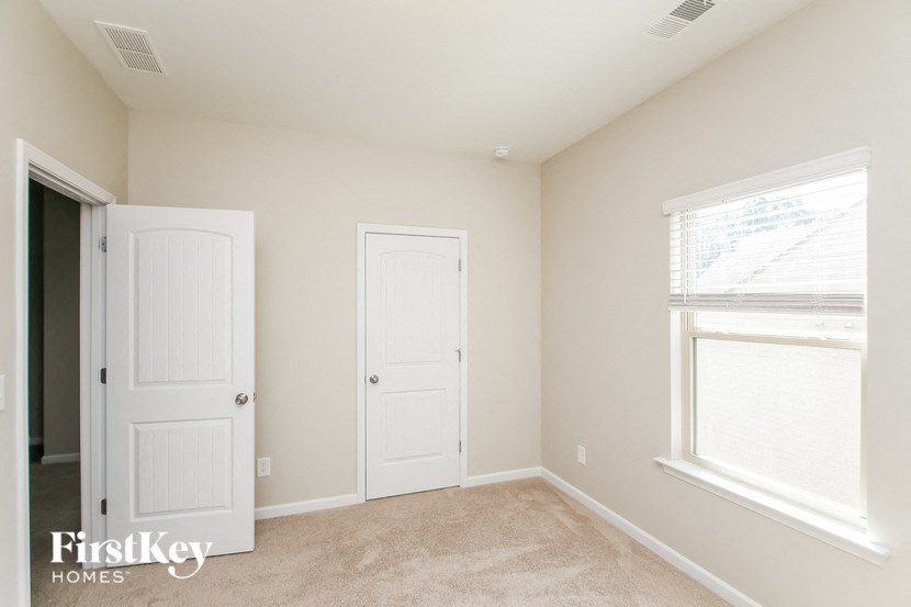 a bedroom with two doors and a window and a carpeted floor