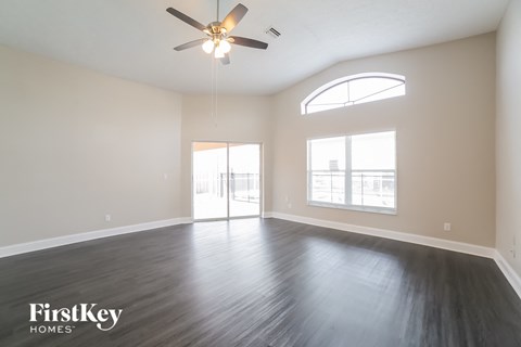 A spacious room with a ceiling fan and sliding glass doors.