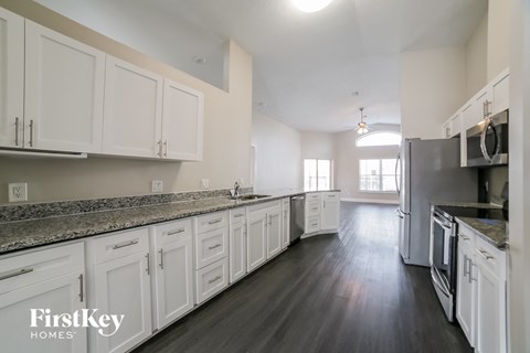 A kitchen with white cabinets and a black countertop.