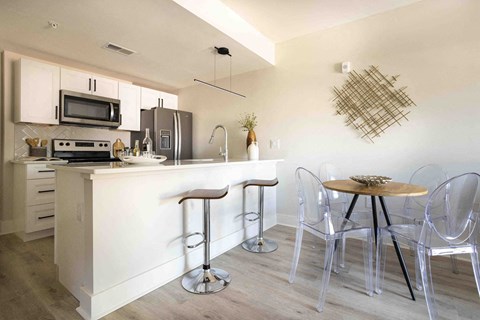 A kitchen with a white counter and bar stools.