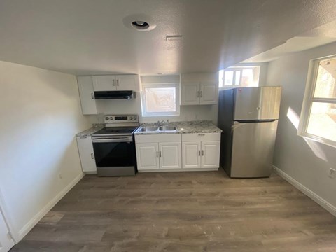 A kitchen with white cabinets and a black fridge.