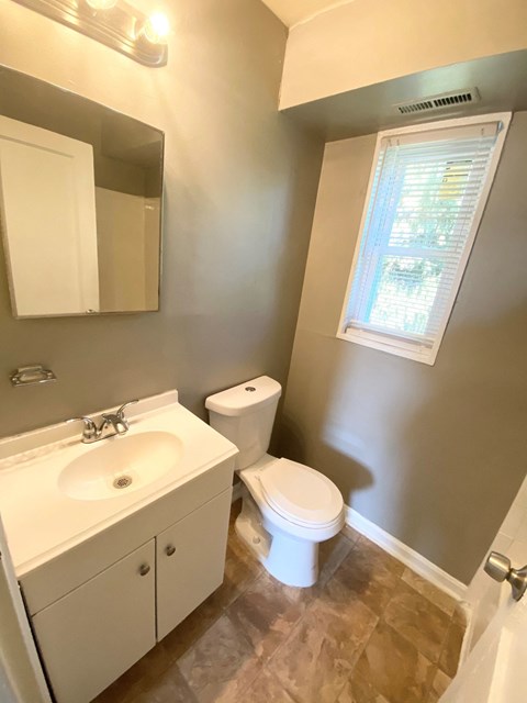 a bathroom with a toilet and a sink and a window