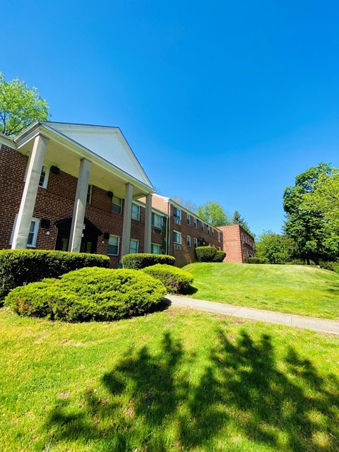 a brick building with a green lawn and a sidewalk