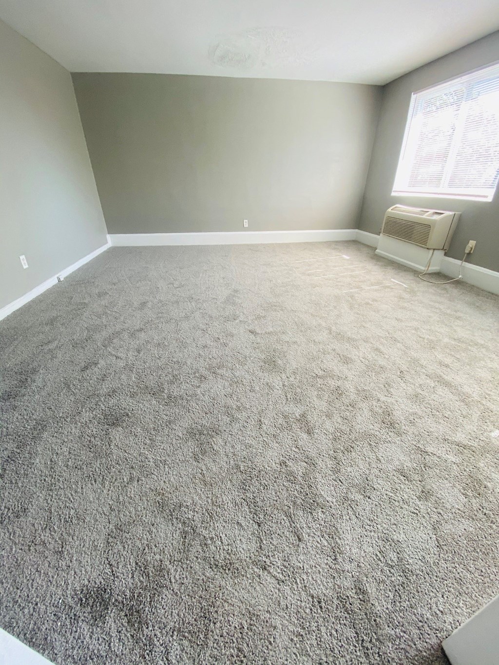 an empty room with a carpeted floor and a window