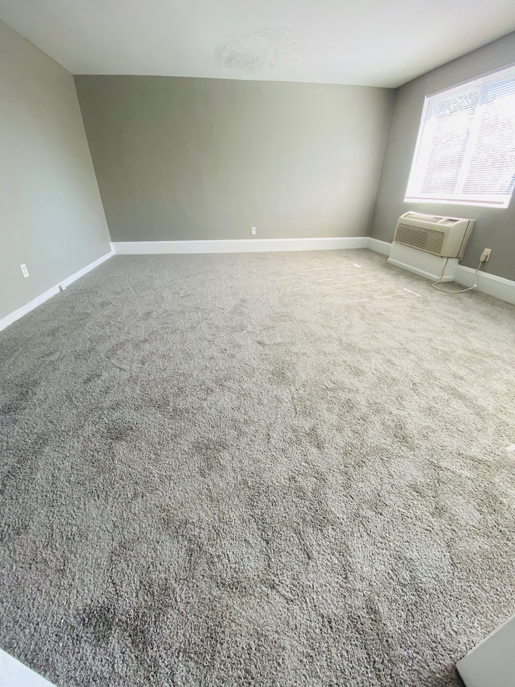 an empty room with a carpeted floor and a window