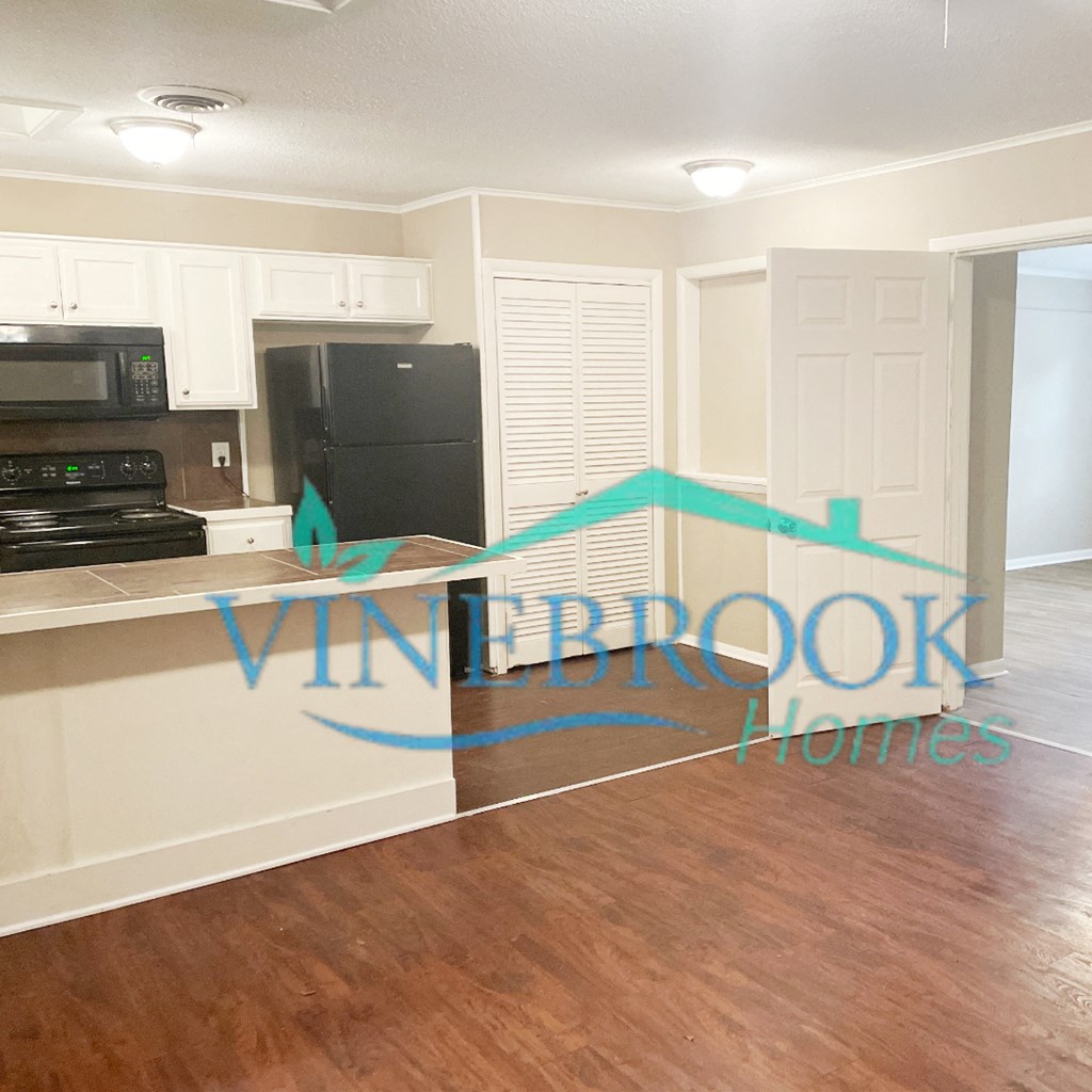 a kitchen with white cabinets and a black refrigerator