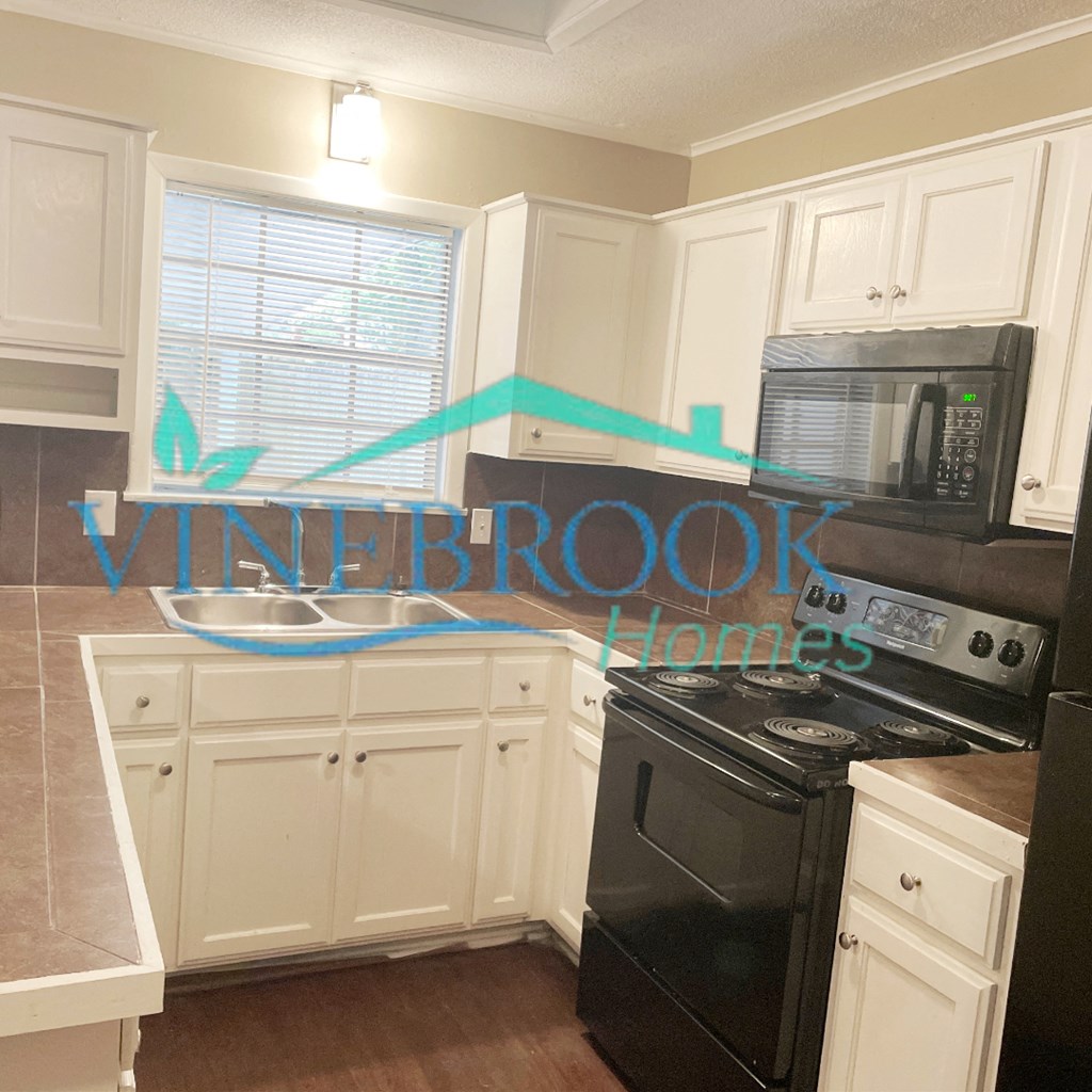 a kitchen with white cabinets and a black stove