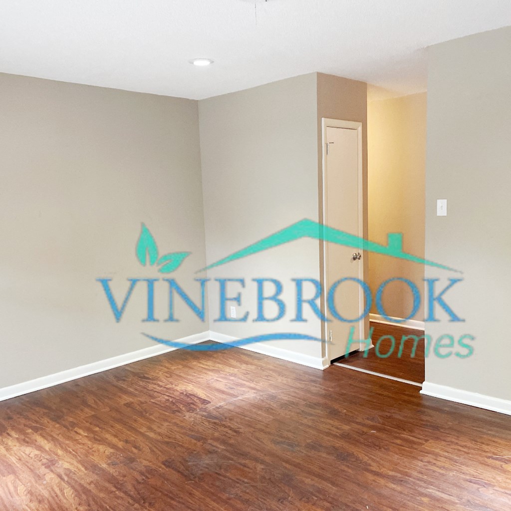 an empty living room with a hard wood floor and a door