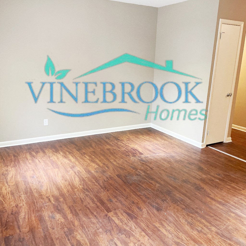an empty room with vinyl flooring and a logo on the wall