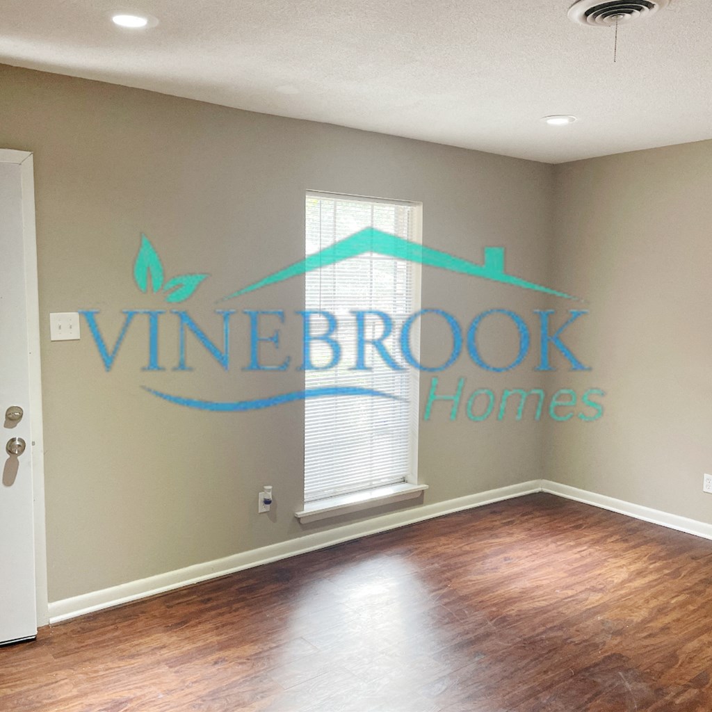 a living room with a window and a wall with a vine brook homes logo