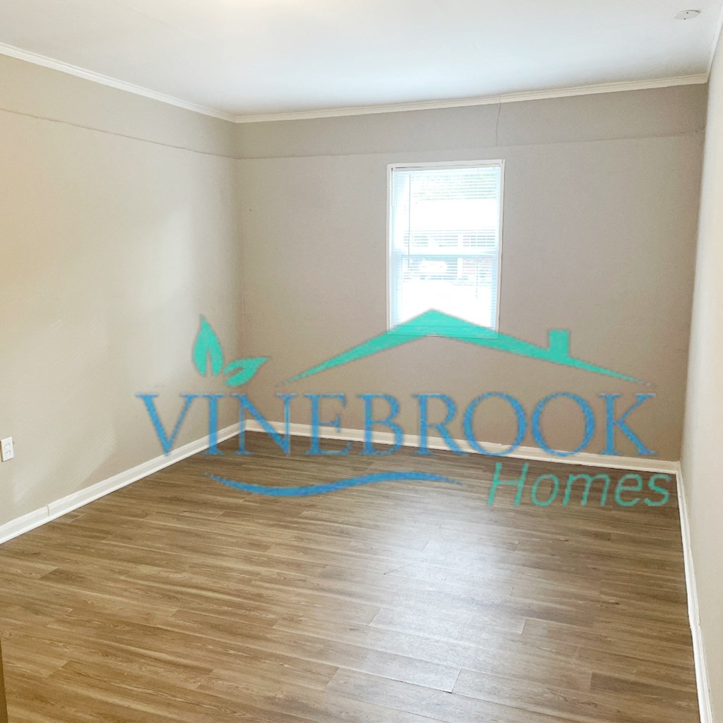 a room with a hardwood floor and a wall with a window and