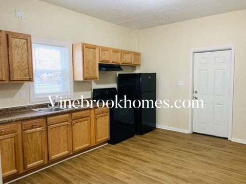 A kitchen with wooden cabinets and a black fridge.